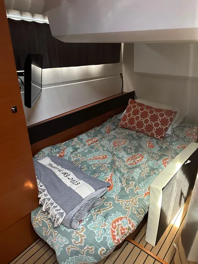 "freedom" Yacht Photos Pics Cozy cabin interior of 2016 Jeanneau NC 14 with patterned bedding and wooden accents.