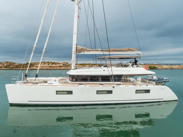 Sunset O Yacht Photos Pics 2019 Lagoon 620 catamaran sailing on calm waters under cloudy skies.