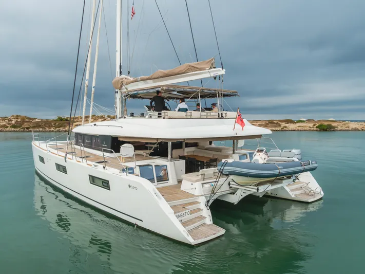 Sunset O Yacht Photos Pics Luxury Lagoon 620 catamaran, 2019 model, anchored in calm waters under cloudy skies.