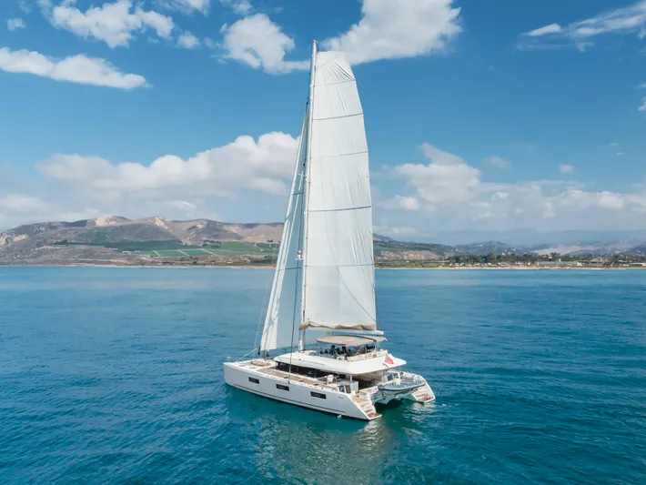 Sunset O Yacht Photos Pics 2019 Lagoon 620 catamaran sailing on clear blue waters under a bright sky.