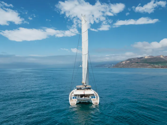 Sunset O Yacht Photos Pics Lagoon 620 catamaran sailing on open sea, 2019 model, under clear blue sky.