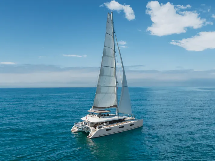 Sunset O Yacht Photos Pics 2019 Lagoon 620 catamaran sailing on open sea under clear blue sky.