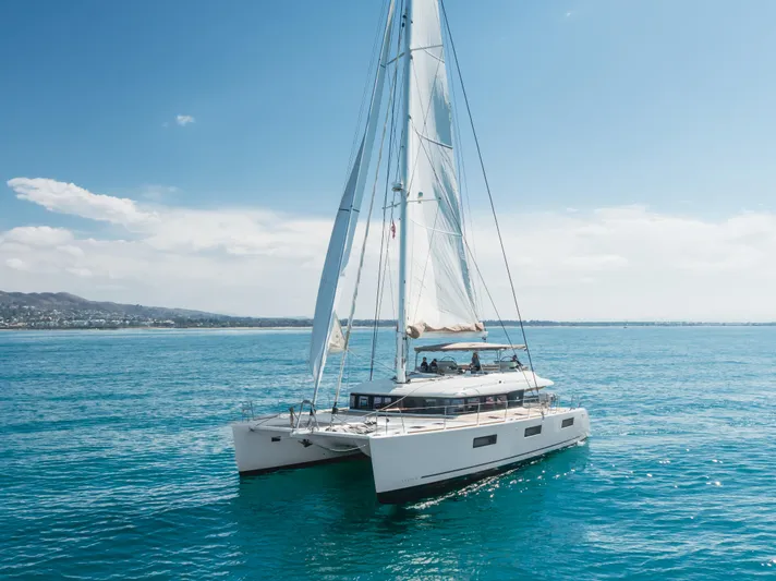Sunset O Yacht Photos Pics 2019 Lagoon 620 catamaran sailing on clear blue ocean under a sunny sky.