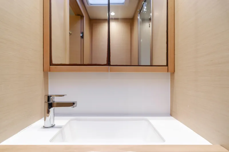 Sunset O Yacht Photos Pics Modern bathroom sink in 2019 Lagoon 620 yacht, featuring sleek faucet and mirrored cabinet.