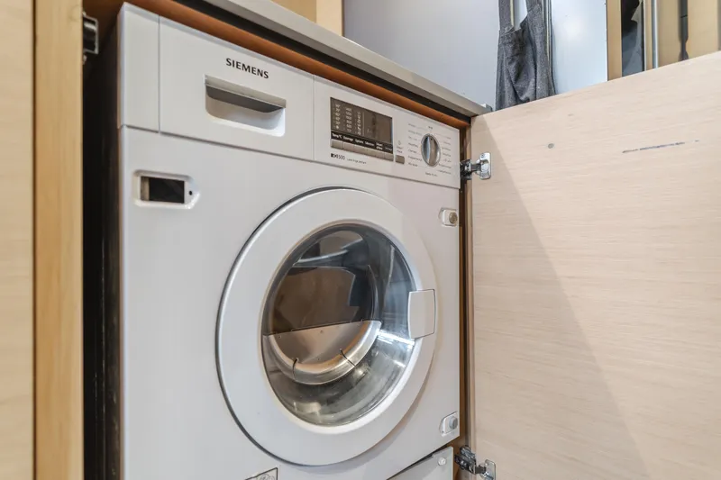 Sunset O Yacht Photos Pics Washing machine inside Lagoon 620 yacht, 2019 model, with open cabinet door.