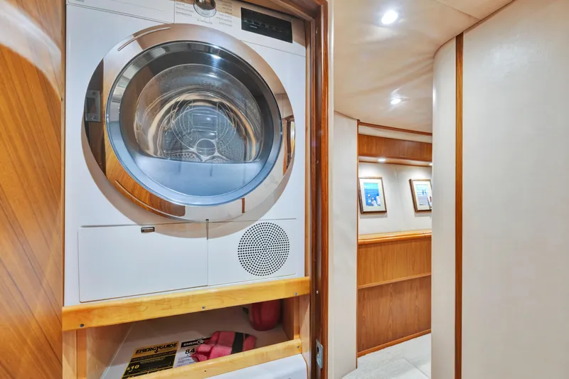 Cutter Bill Yacht Photos Pics Laundry area inside 2011 Viking 70 Convertible yacht with wood paneling and framed artwork.