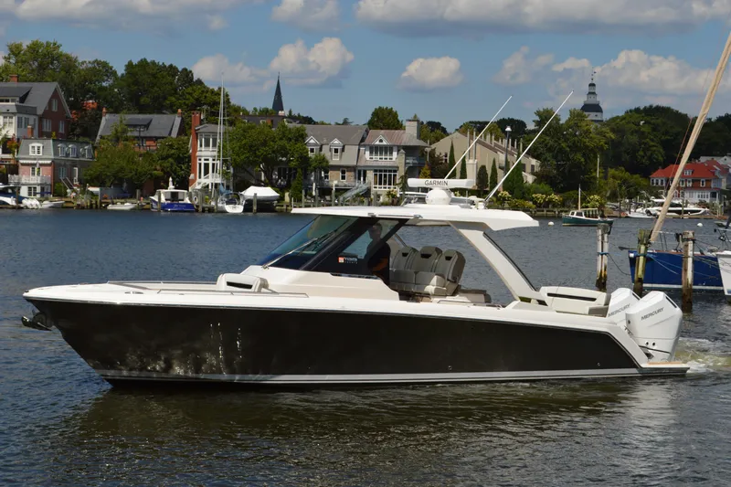 Station Break Yacht Photos Pics 2024 Tiara Yachts 34 LS cruising on a scenic waterfront with houses in the background.