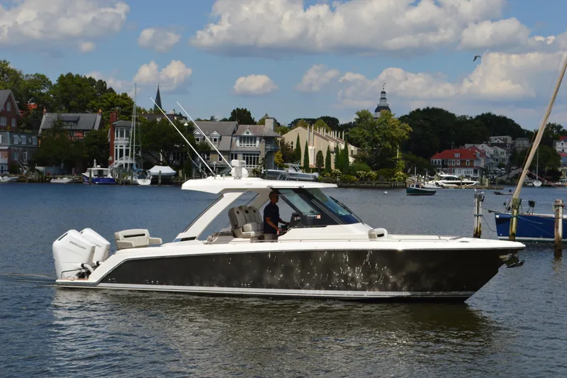 Station Break Yacht Photos Pics 2024 Tiara Yachts 34 LS cruising on a scenic waterfront with houses in the background.
