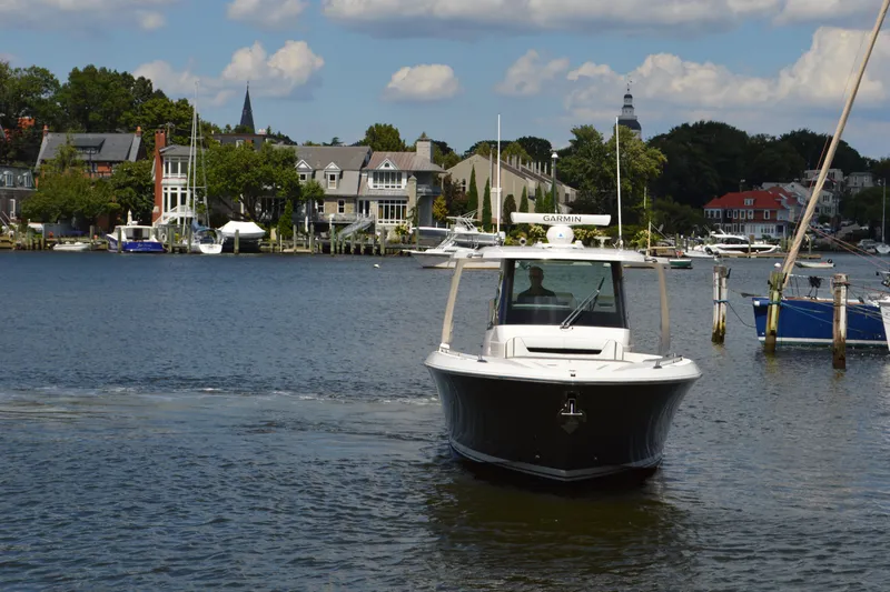 Station Break Yacht Photos Pics 2024 Tiara Yachts 34 LS cruising on a scenic waterfront with houses and boats.