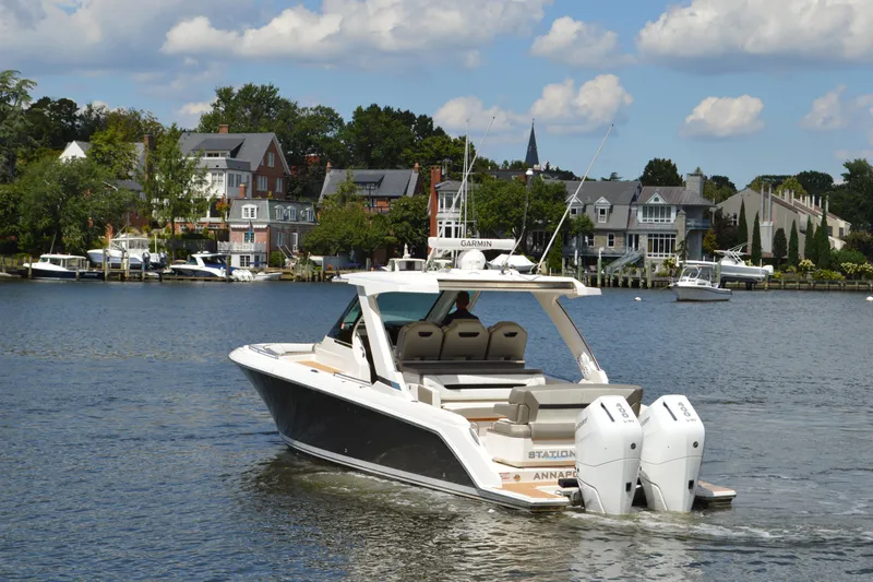 Station Break Yacht Photos Pics 2024 Tiara Yachts 34 LS cruising on a scenic waterfront with houses in the background.