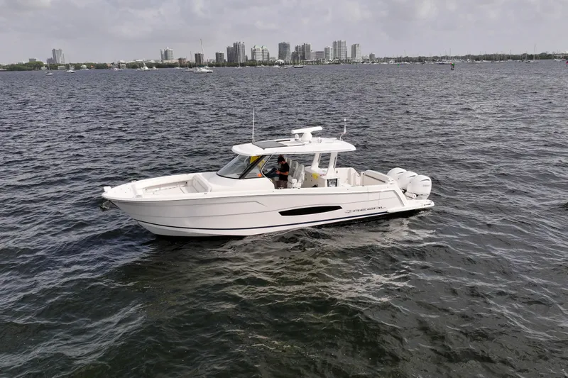  Yacht Photos Pics 2023 Regal 38 SAV boat cruising on a city waterfront.