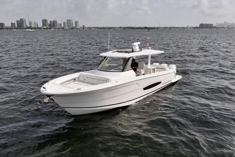  Yacht Photos Pics 2023 Regal 38 SAV boat cruising on open water near city skyline.