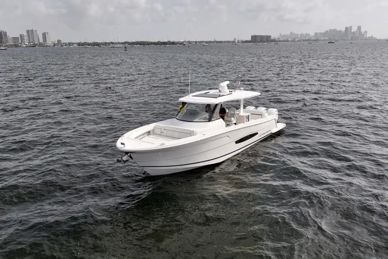  Yacht Photos Pics 2023 Regal 38 SAV boat cruising on open water with city skyline in background.