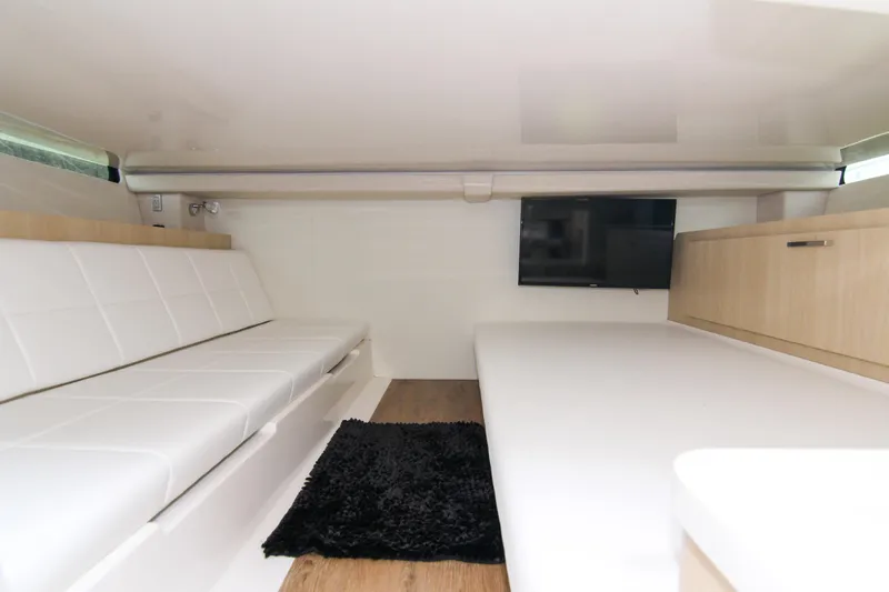  Yacht Photos Pics 2023 Regal 38 SAV interior with white seating, TV, and black rug.
