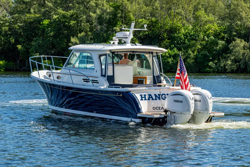  Yacht Photos Pics 2020 Back Cove 340 boat cruising on a scenic river with lush greenery.