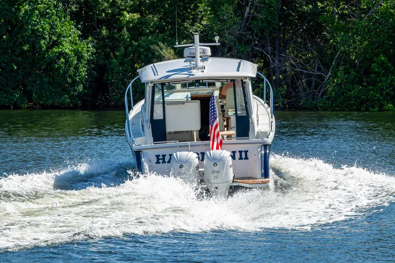  Yacht Photos Pics 2020 Back Cove 340 boat cruising on a lake with American flag, surrounded by trees.
