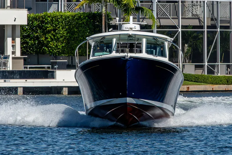  Yacht Photos Pics 2020 Back Cove 340 boat cruising on water near modern waterfront property.