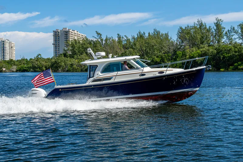  Yacht Photos Pics 2020 Back Cove 340 boat cruising on water with American flag, cityscape background.