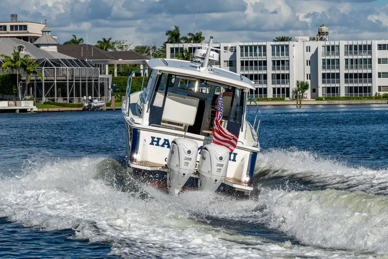  Yacht Photos Pics 2020 Back Cove 340 boat cruising on water with American flag, modern buildings in background.