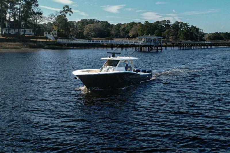O-sea-d Yacht Photos Pics 2020 Scout 380 LXF boat cruising on a scenic river near a wooden dock.