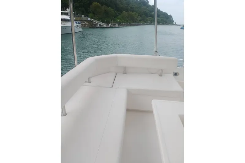  Yacht Photos Pics Leopard 43 Powercat yacht with white seating, docked near lush green shoreline.