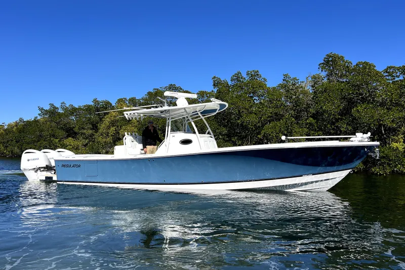  Yacht Photos Pics 2018 Regulator 34 Center Console boat cruising on clear water with lush greenery background.