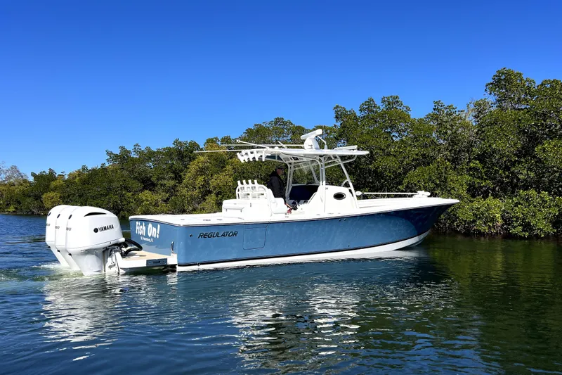  Yacht Photos Pics 2018 Regulator 34 Center Console boat cruising on a sunny day with lush greenery.