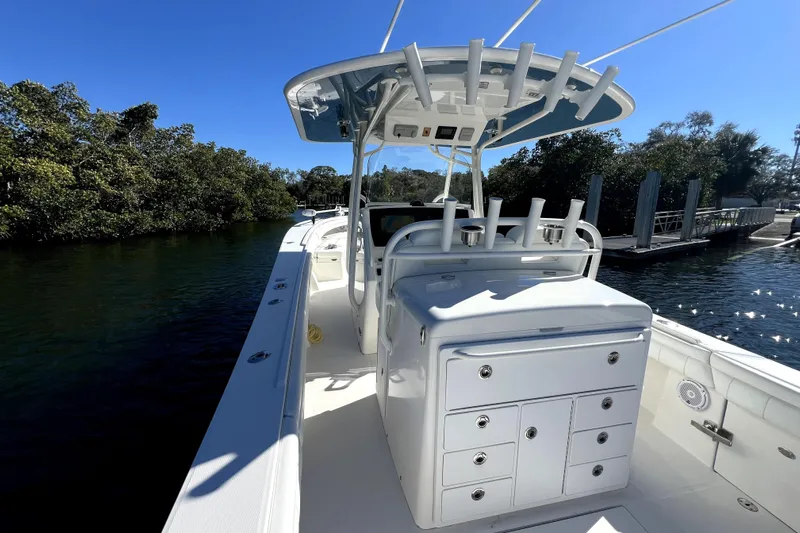  Yacht Photos Pics 2018 Regulator 34 Center Console boat on calm water, surrounded by lush greenery.