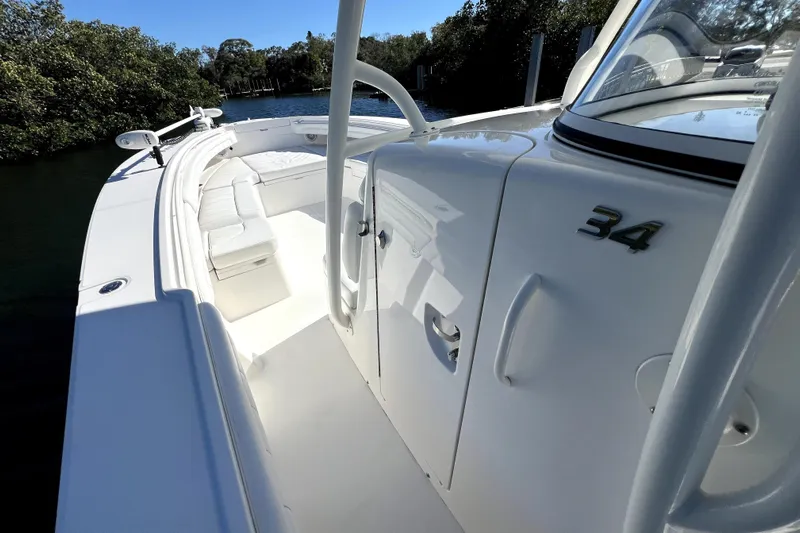  Yacht Photos Pics 2018 Regulator 34 Center Console boat, white interior, sleek design, docked near lush greenery.