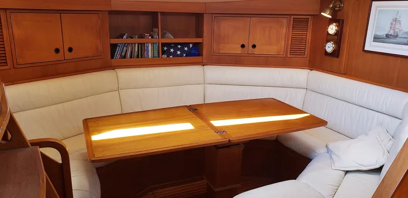 Hasard III Yacht Photos Pics Interior of 1986 Baltic 48 DP sailboat with wooden table and white cushioned seating.