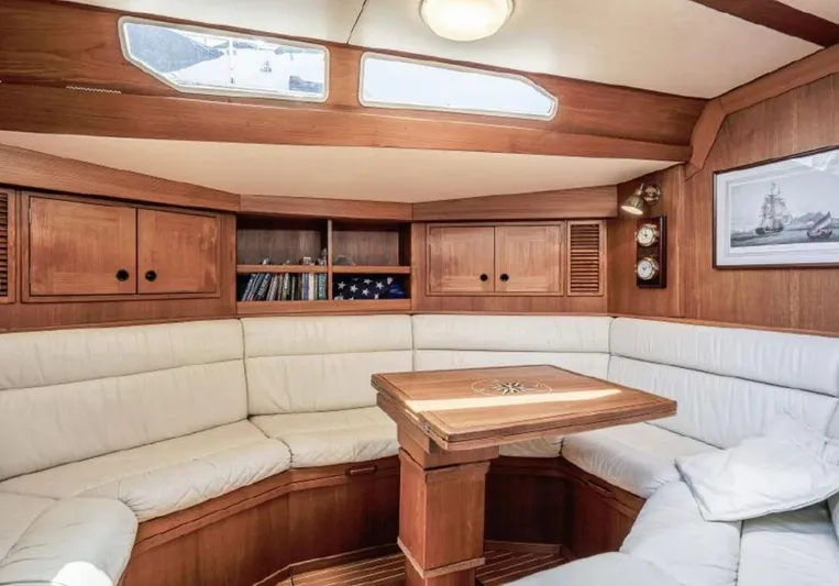 Hasard III Yacht Photos Pics Luxurious interior of 1986 Baltic 48 DP yacht with white leather seating and wooden cabinetry.