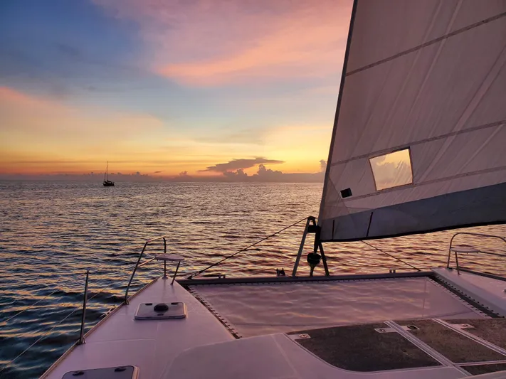  Yacht Photos Pics Sailing on a 2011 Leopard 46 catamaran at sunset over calm ocean waters.