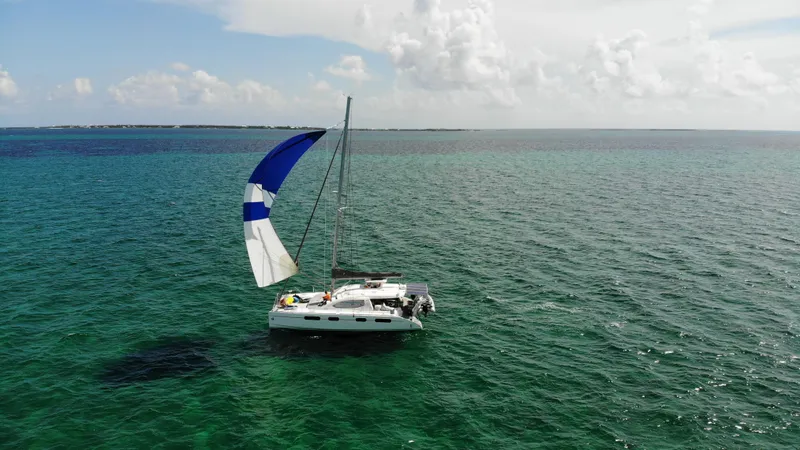  Yacht Photos Pics Sailing catamaran Leopard 46 on clear ocean waters under a partly cloudy sky.