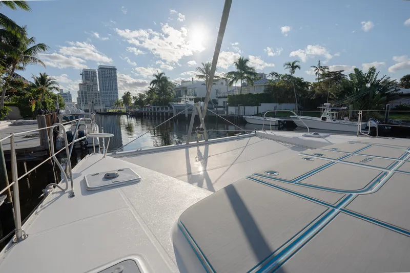  Yacht Photos Pics Leopard 46 catamaran docked in a sunny marina, surrounded by palm trees and buildings.