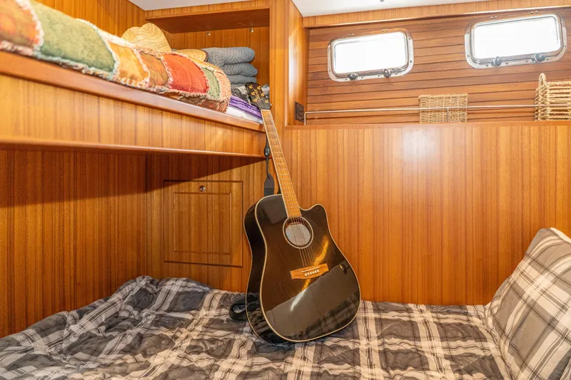 Northern Reign Yacht Photos Pics Cozy cabin interior of 2020 North Pacific 45 Pilothouse with guitar and plaid bedding.