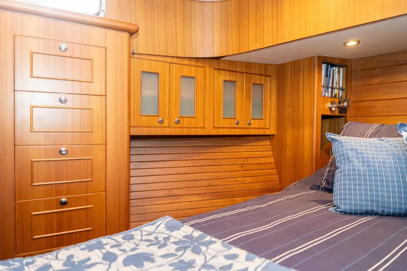 Northern Reign Yacht Photos Pics Cozy cabin interior of 2020 North Pacific 45 Pilothouse with wood paneling and striped bedding.