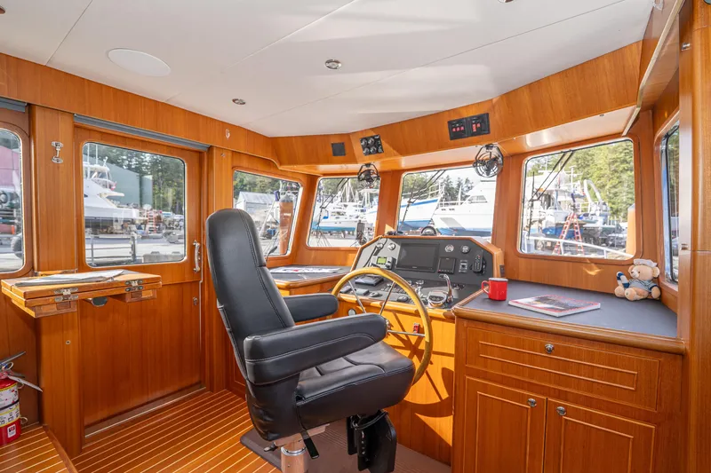 Northern Reign Yacht Photos Pics Pilothouse interior of 2020 North Pacific 45, featuring wood paneling and navigation equipment.