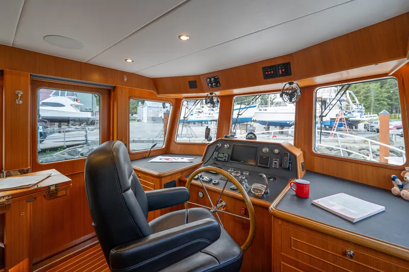 Northern Reign Yacht Photos Pics Pilothouse interior of 2020 North Pacific 45, featuring helm, windows, and wooden finish.