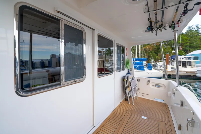 Northern Reign Yacht Photos Pics 2020 North Pacific 45 Pilothouse yacht deck with fishing rods and marina view.