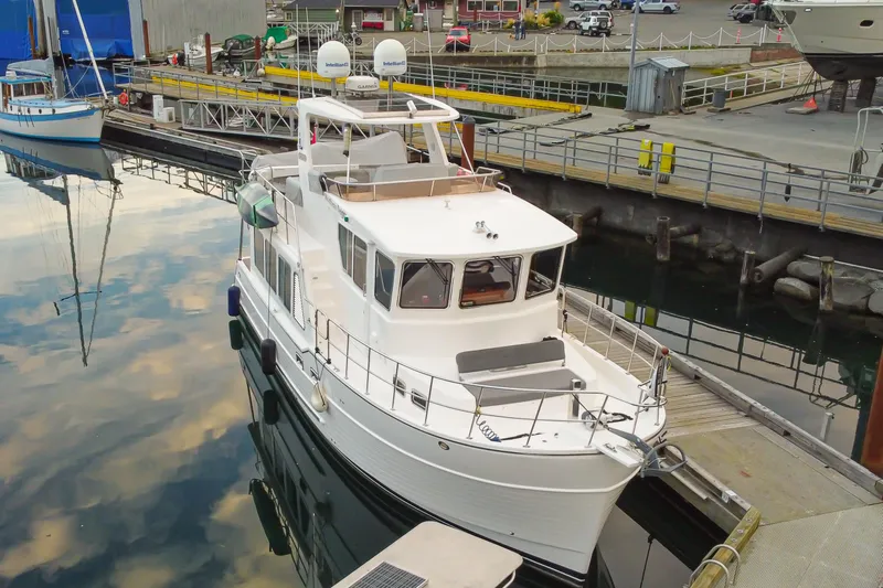Northern Reign Yacht Photos Pics 2020 North Pacific 45 Pilothouse yacht docked at marina, reflecting on calm water.
