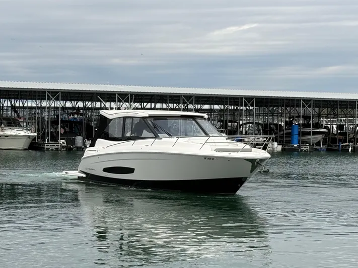  Yacht Photos Pics 2023 Regal 360 Grande Coupe yacht cruising near marina under cloudy sky.