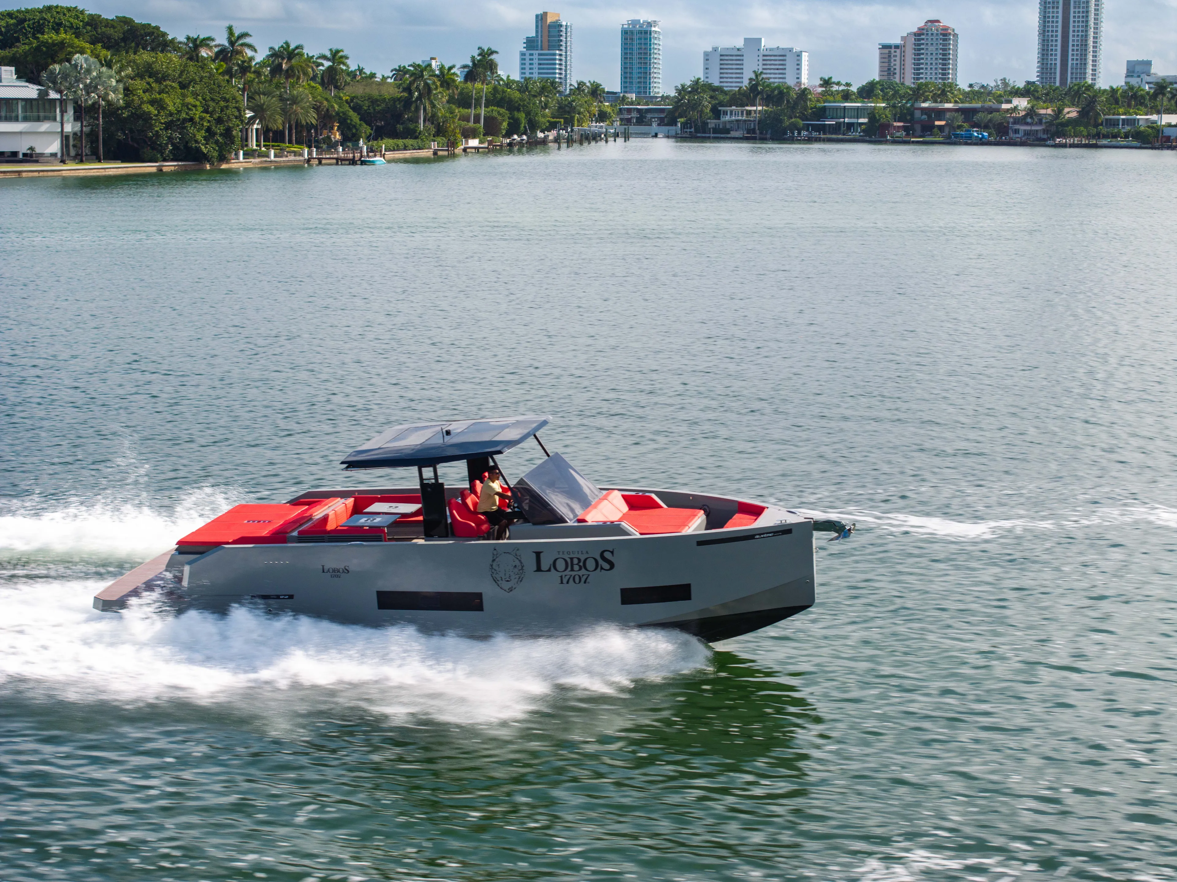 Painkiller Yacht Photos Pics 2023 De Antonio Yachts D42 Open cruising on a scenic waterway with city skyline backdrop.