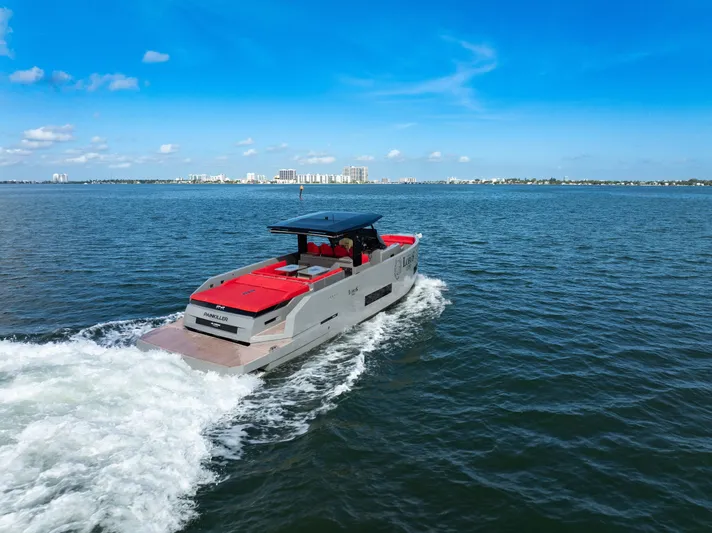 Painkiller Yacht Photos Pics 2023 De Antonio Yachts D42 Open cruising on a sunny day, city skyline in background.
