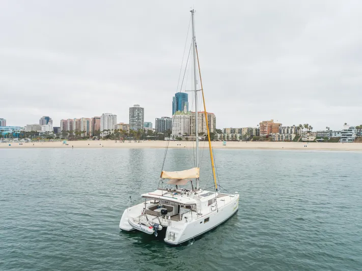 Limoncello Yacht Photos Pics 2016 Lagoon 450F catamaran sailing near urban coastline with skyscrapers in background.