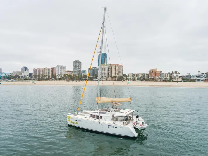 Limoncello Yacht Photos Pics 2016 Lagoon 450F catamaran sailing near a city shoreline with buildings in the background.