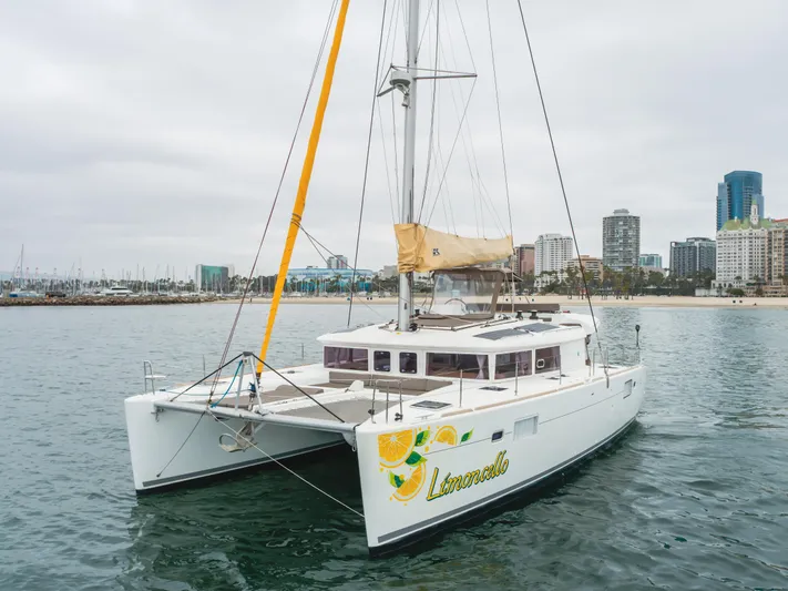 Limoncello Yacht Photos Pics Lagoon 450F catamaran 2016 on water near city skyline, overcast sky.
