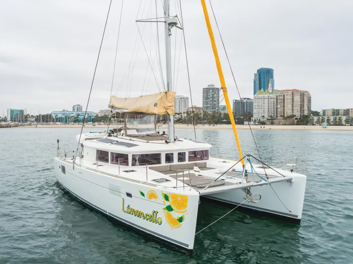 Limoncello Yacht Photos Pics 2016 Lagoon 450F catamaran sailing near urban skyline, featuring "Limoncello" design on hull.