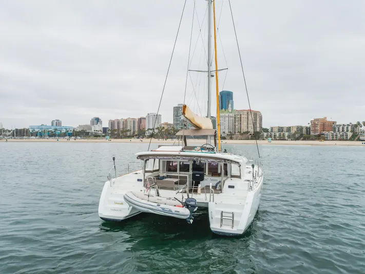 Limoncello Yacht Photos Pics 2016 Lagoon 450F catamaran anchored near city skyline, calm waters, overcast sky.