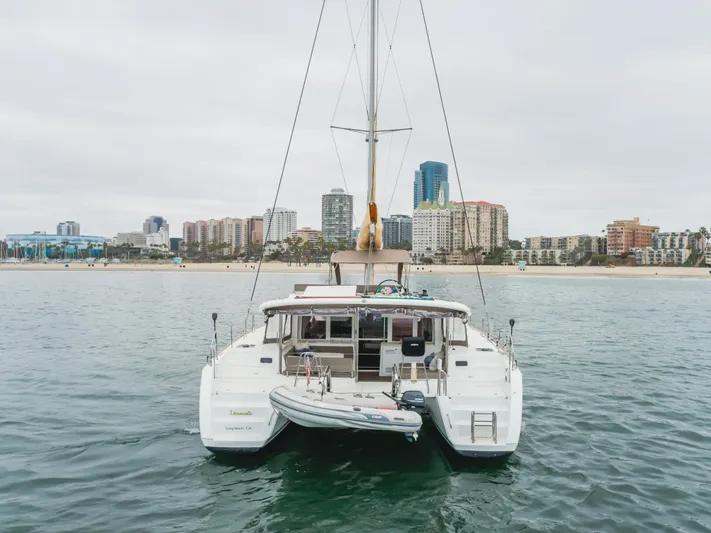 Limoncello Yacht Photos Pics 2016 Lagoon 450F catamaran anchored near urban coastline with city skyline in background.