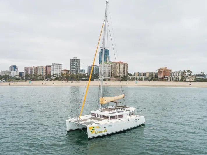 Limoncello Yacht Photos Pics 2016 Lagoon 450F catamaran sailing near urban coastline with skyscrapers in background.
